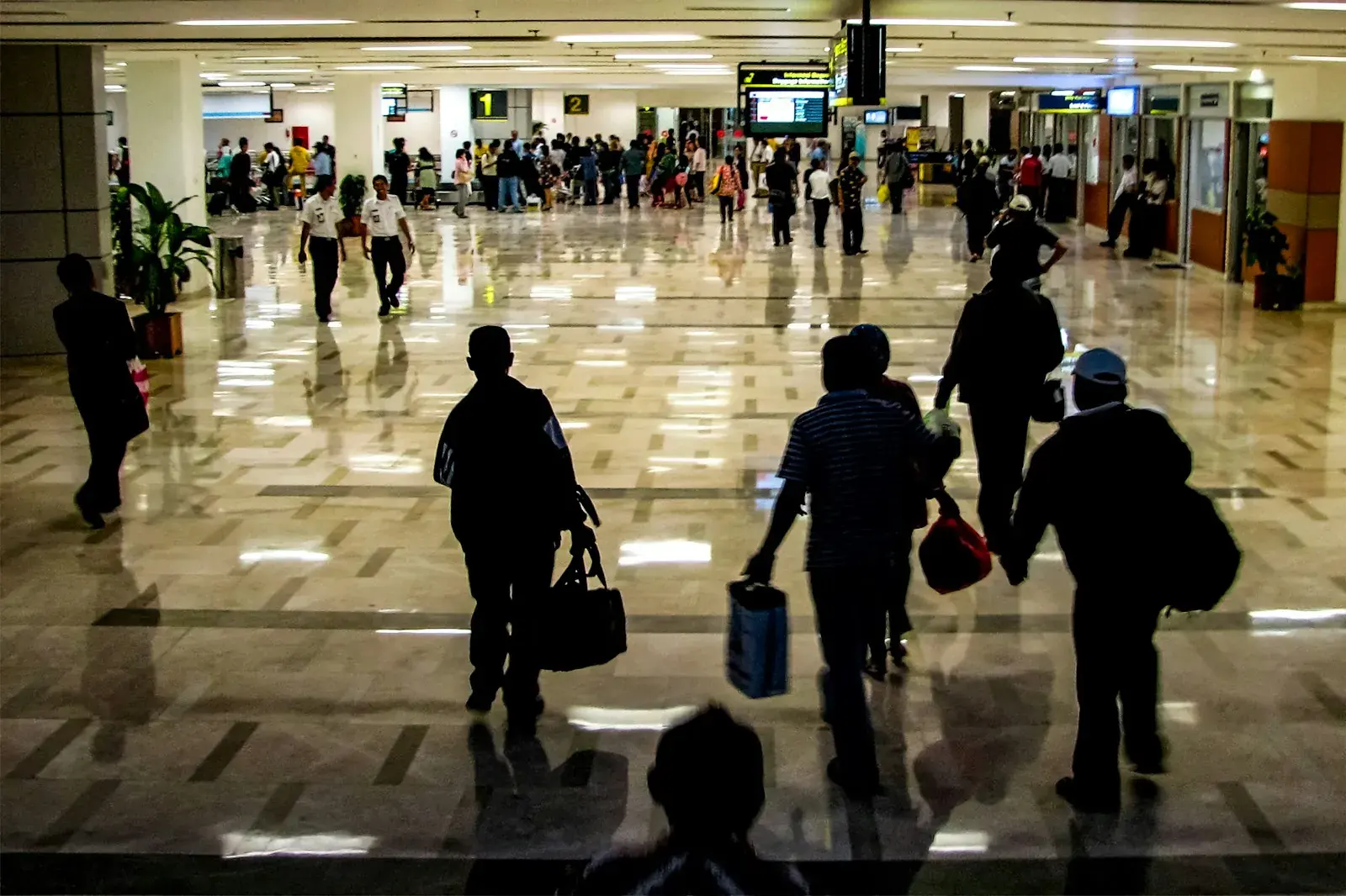 Viajeros con equipaje caminando por un luminoso vestíbulo de aeropuerto