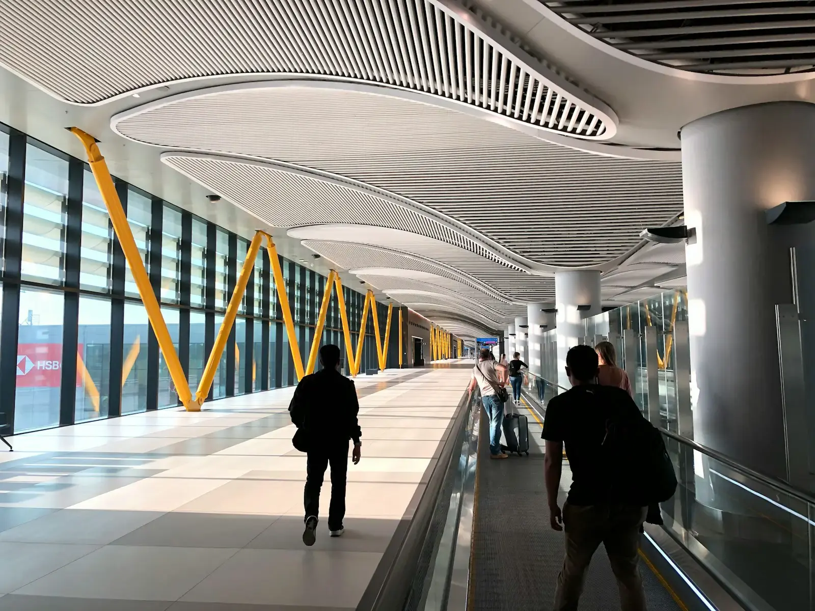 Viajeros caminando por un largo y luminoso pasillo de aeropuerto