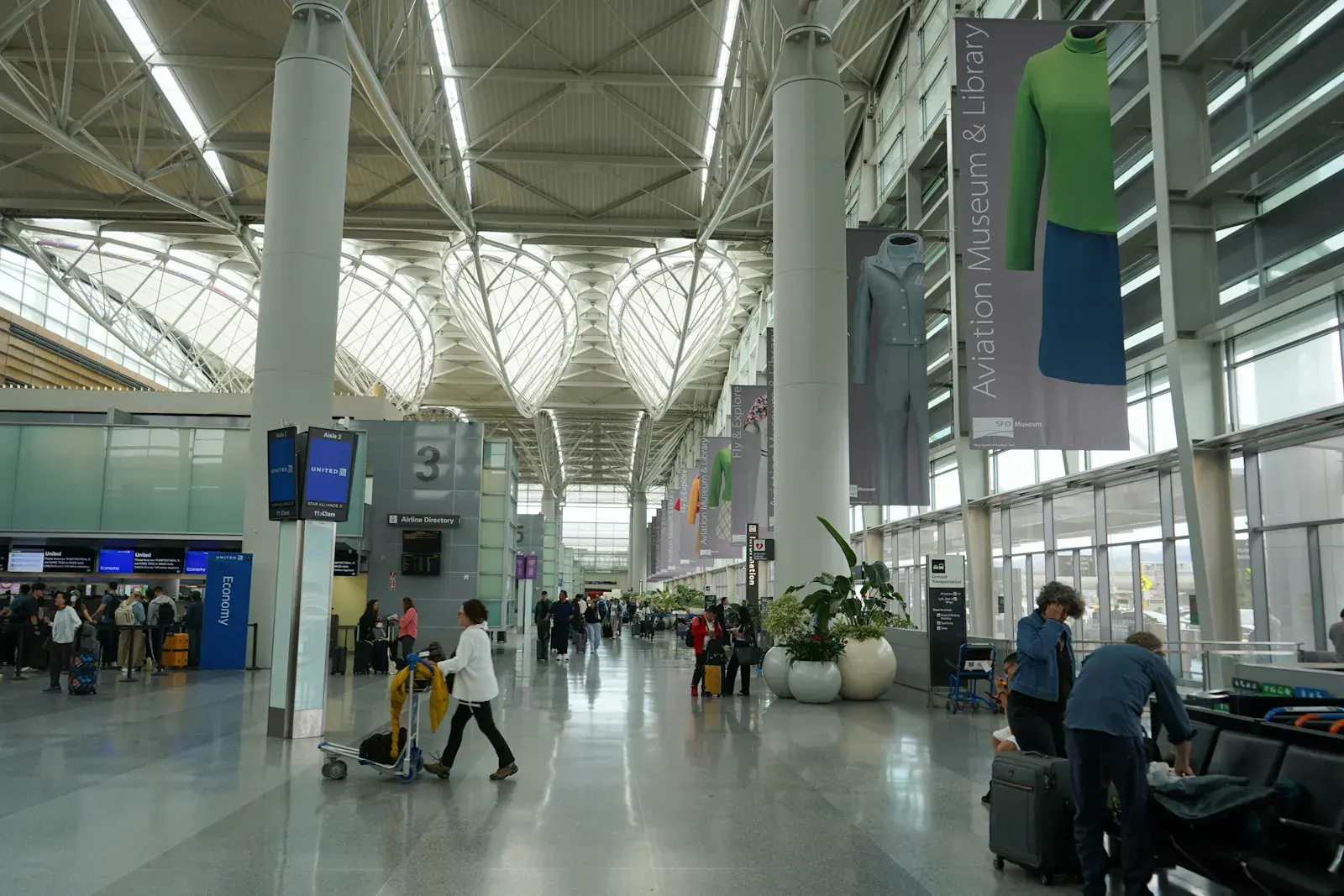 Personas caminando por un luminoso vestíbulo de facturación de aeropuerto