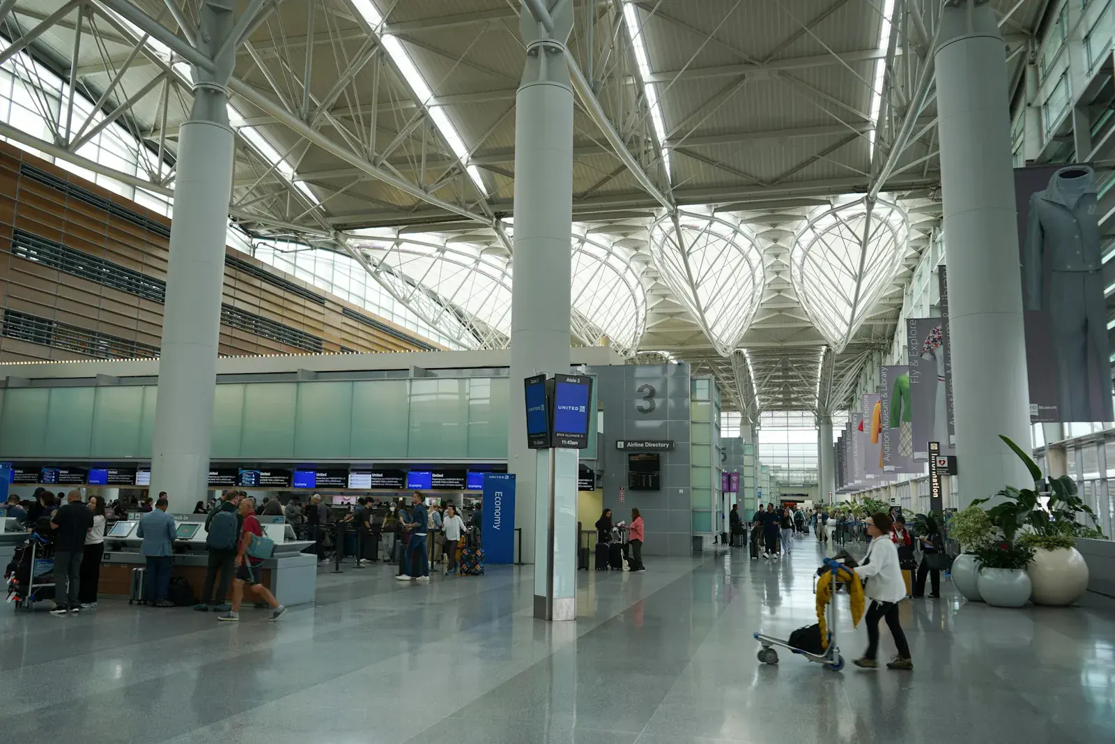 넓은 공항 터미널에서 짐을 밀며 걷는 여행객들