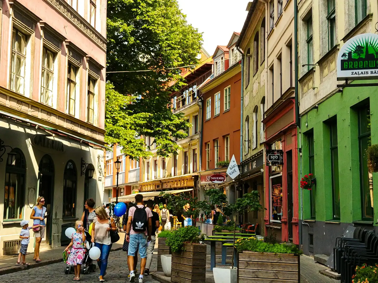 People walking in the sunshine along a street lined with colourful buildings