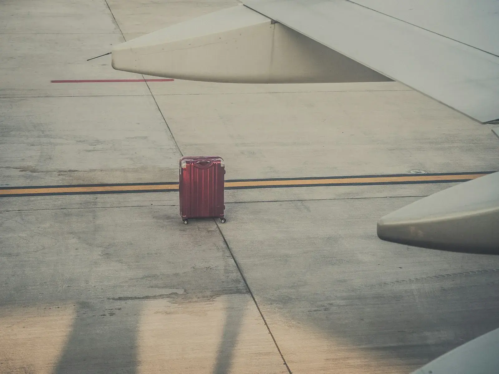 飛行機の翼の下に置かれたスーツケース