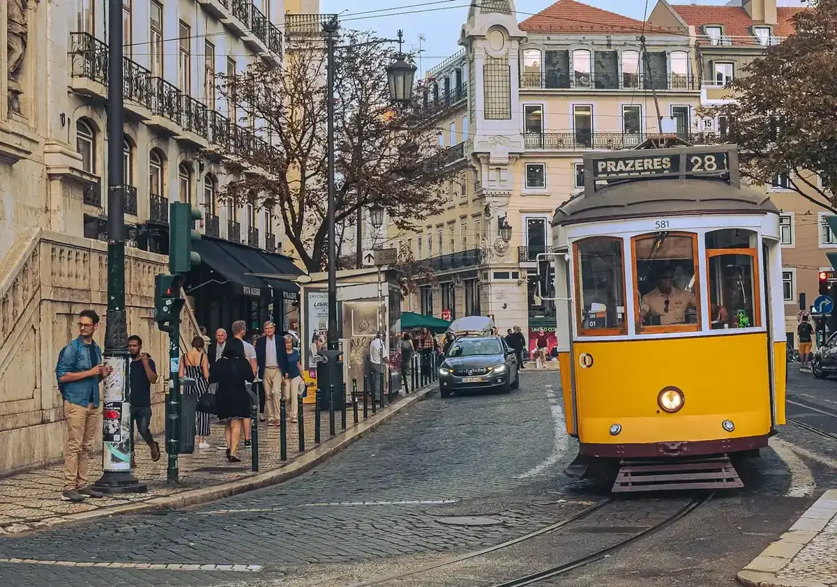 A yellow tram and people walking along the street